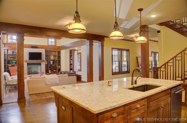 kitchen featuring a wealth of natural light, an island with sink, hanging light fixtures, and sink