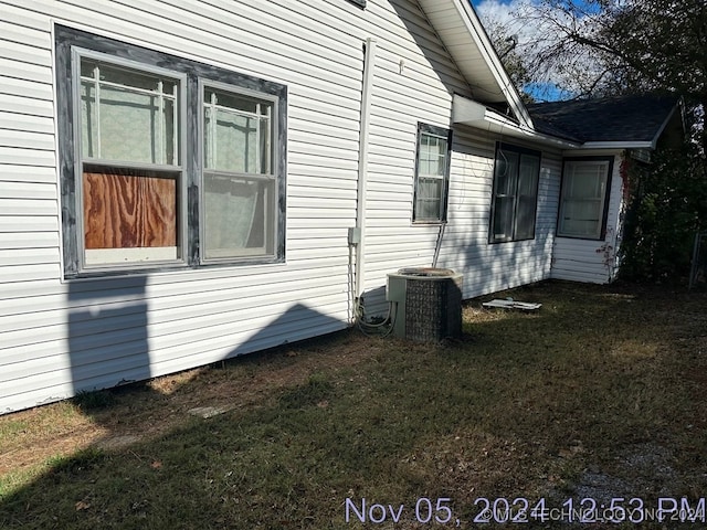 view of side of property with a lawn and cooling unit