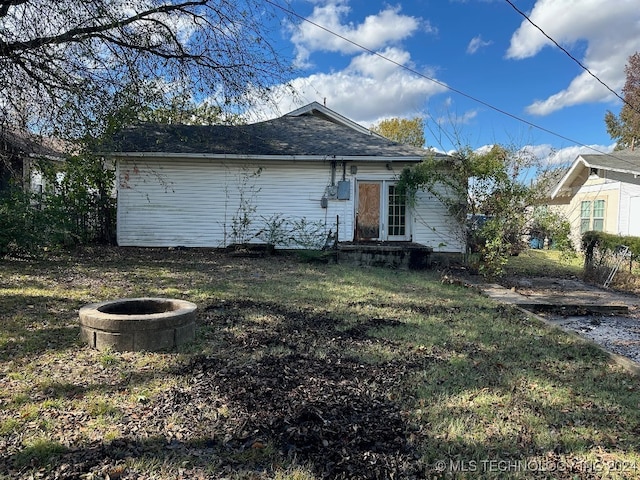 back of property with a lawn and a fire pit