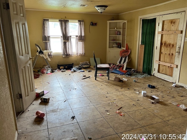 misc room featuring tile patterned flooring, a textured ceiling, and ornamental molding