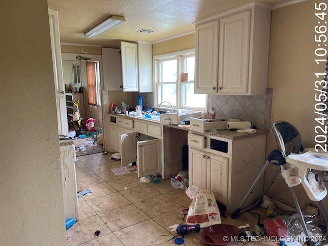 kitchen with light tile patterned floors, a textured ceiling, and ornamental molding