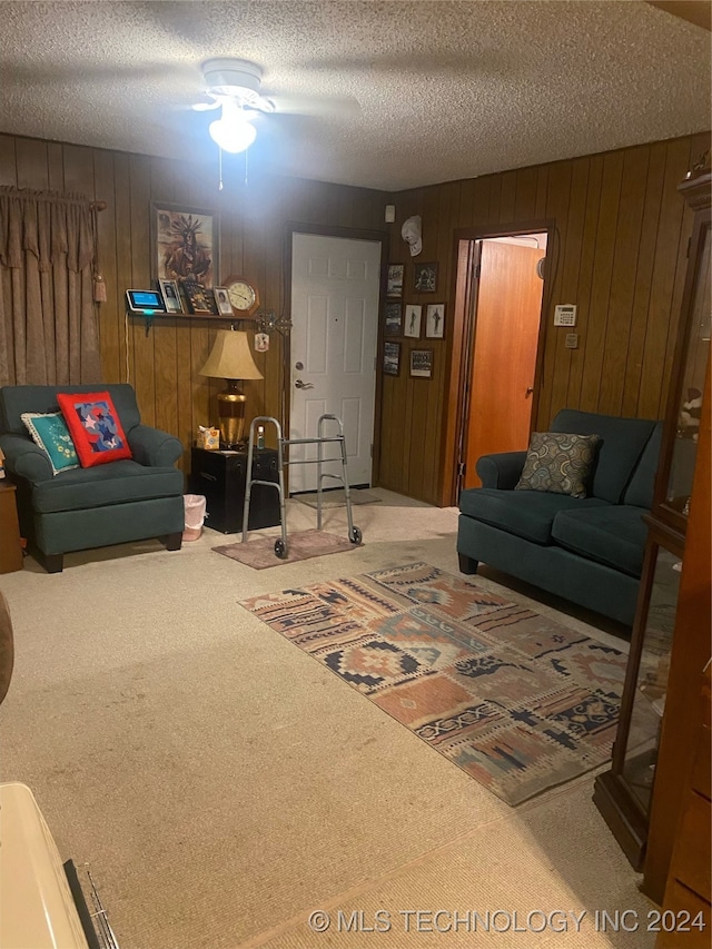 living room with carpet, ceiling fan, a textured ceiling, and wooden walls