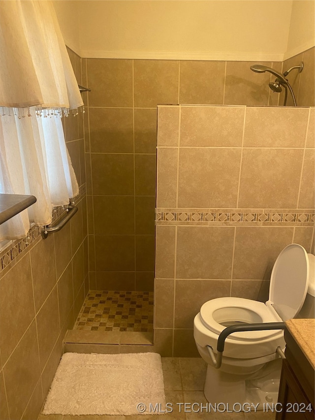 bathroom with vanity, tile patterned flooring, toilet, tile walls, and a tile shower