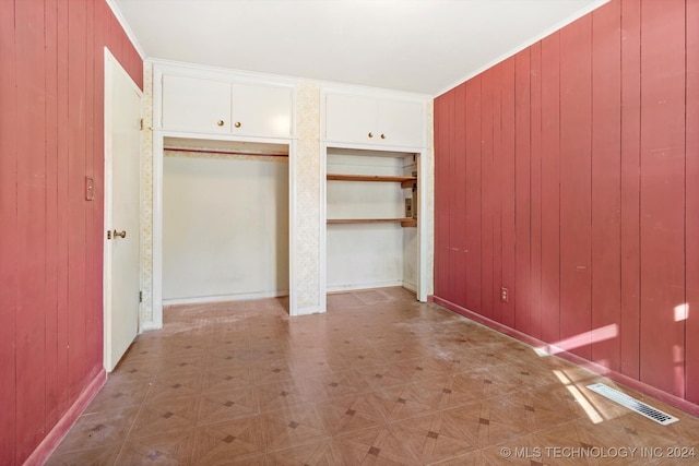 unfurnished bedroom with wooden walls, light parquet flooring, and ornamental molding