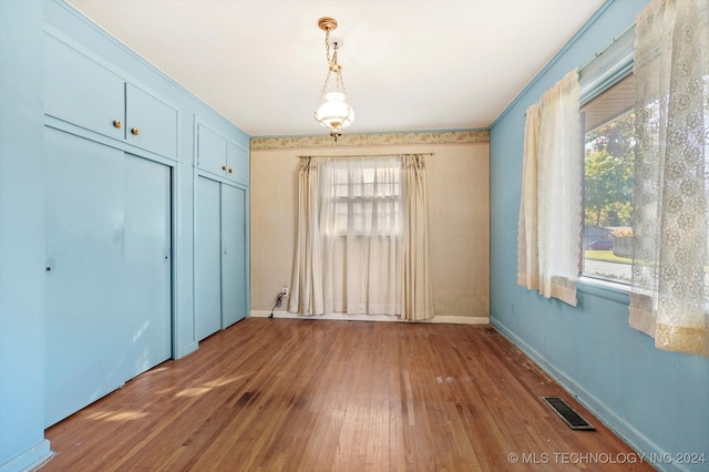 unfurnished bedroom featuring hardwood / wood-style floors, two closets, and multiple windows