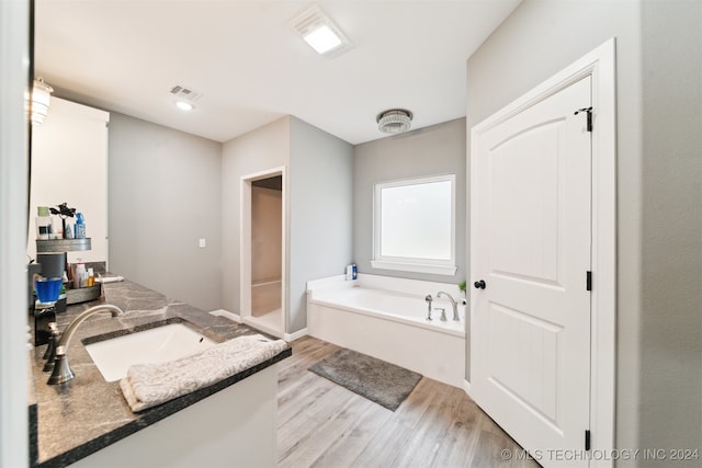 bathroom featuring hardwood / wood-style flooring, vanity, and a tub to relax in