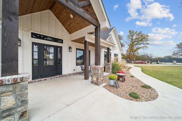 view of exterior entry with covered porch and a yard