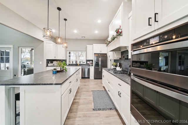 kitchen featuring tasteful backsplash, a center island, white cabinets, and stainless steel appliances