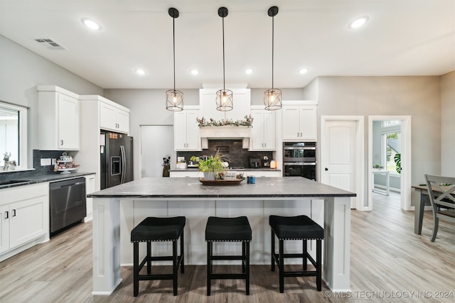 kitchen featuring appliances with stainless steel finishes, a kitchen island, light hardwood / wood-style floors, white cabinetry, and hanging light fixtures