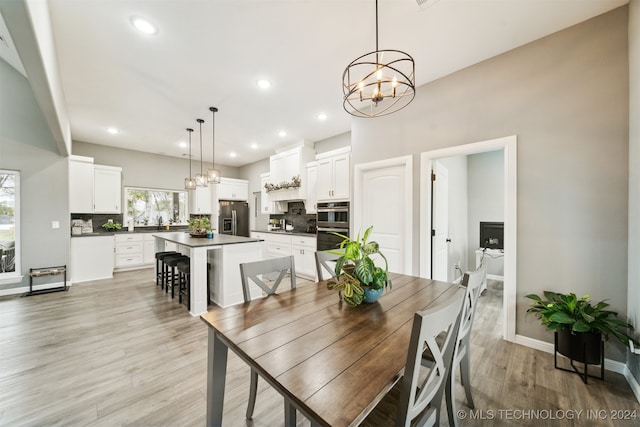 dining area featuring light wood-type flooring and a notable chandelier