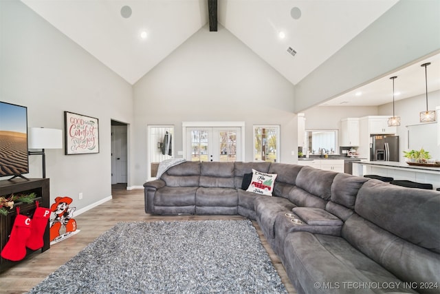 living room with beamed ceiling, french doors, light hardwood / wood-style flooring, and high vaulted ceiling