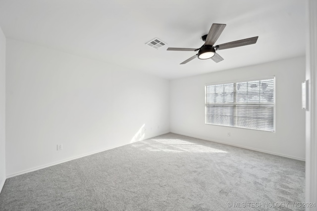 carpeted spare room featuring visible vents, baseboards, and a ceiling fan