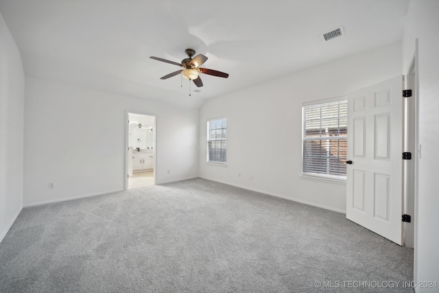 unfurnished bedroom featuring visible vents, baseboards, carpet, ensuite bath, and a ceiling fan