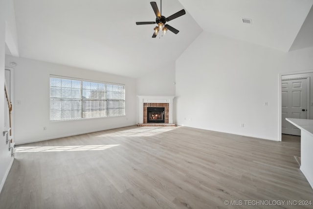 unfurnished living room featuring light wood-type flooring, high vaulted ceiling, a brick fireplace, and ceiling fan