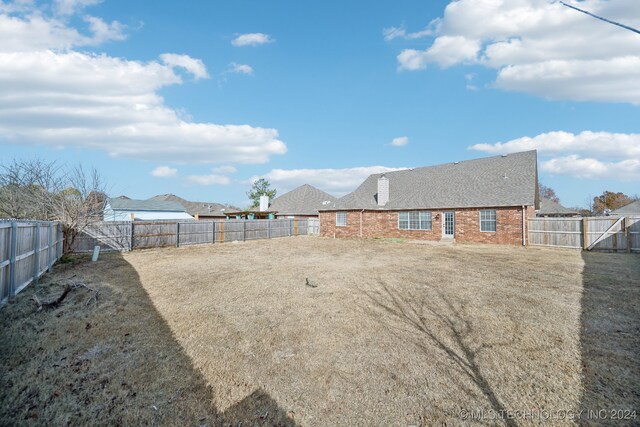 rear view of house featuring a fenced backyard and brick siding