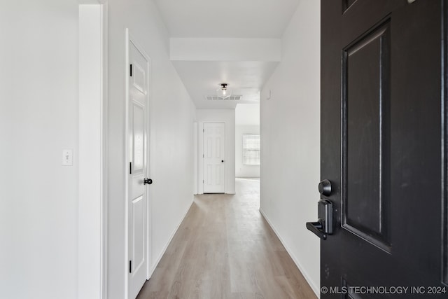 corridor featuring visible vents, baseboards, and light wood-style floors