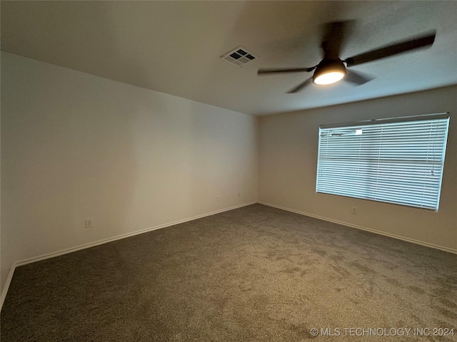 spare room with visible vents, dark carpet, baseboards, and ceiling fan