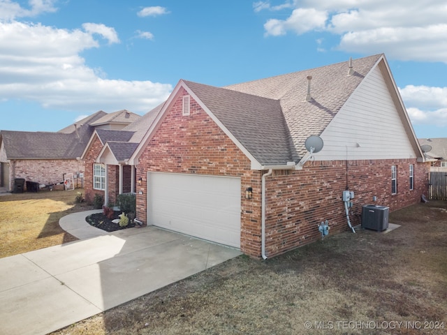 view of front of property with a front lawn, central AC unit, and a garage