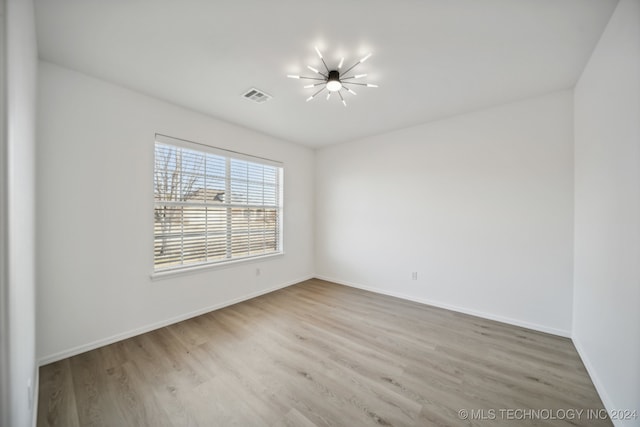 empty room with visible vents, baseboards, and wood finished floors