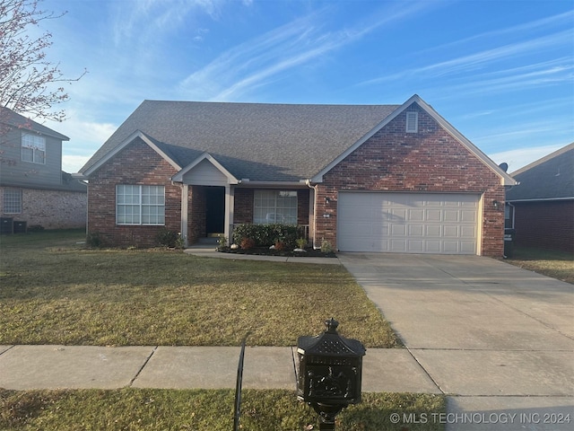 view of front of home featuring a front yard, driveway, roof with shingles, a garage, and brick siding