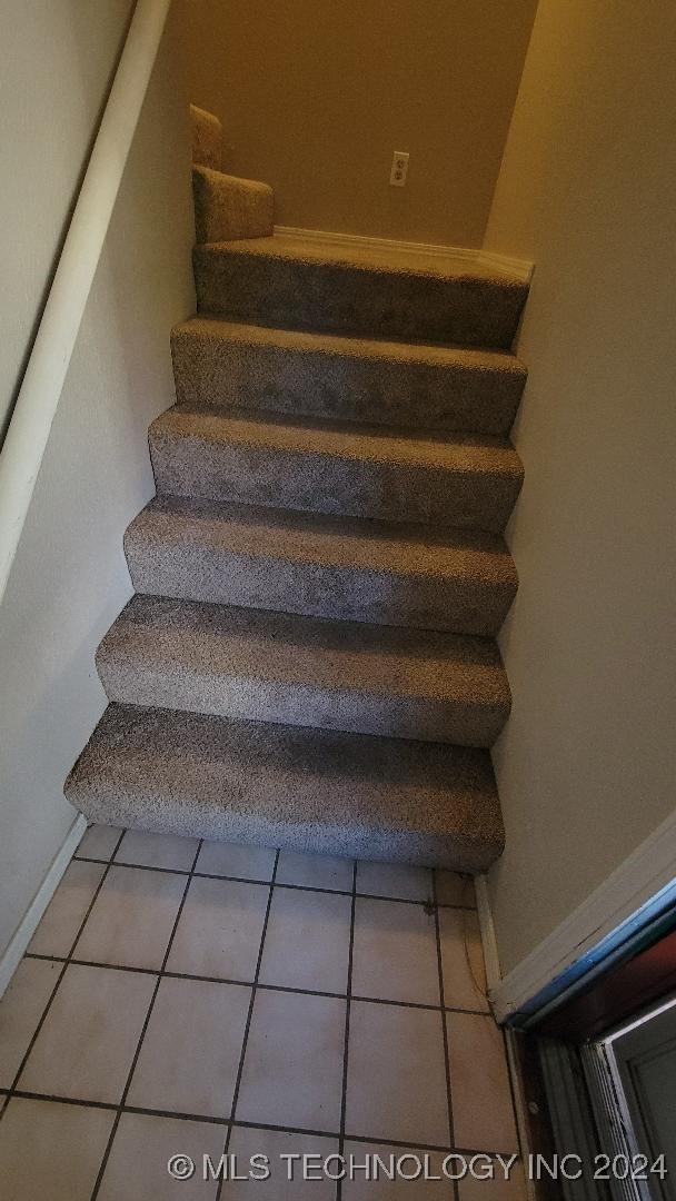 stairway with tile patterned floors and baseboards