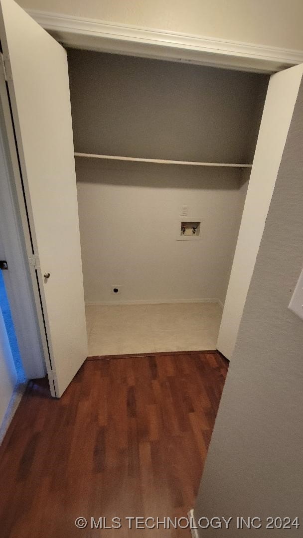 clothes washing area featuring wood finished floors, washer hookup, and laundry area