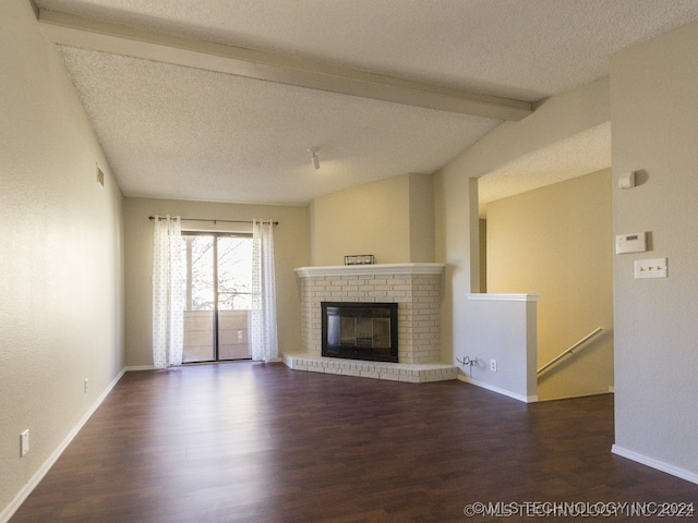 unfurnished living room featuring a fireplace, a textured ceiling, wood finished floors, and beamed ceiling