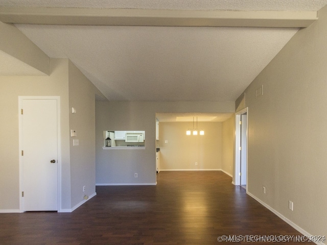 spare room featuring a notable chandelier, dark wood finished floors, and baseboards