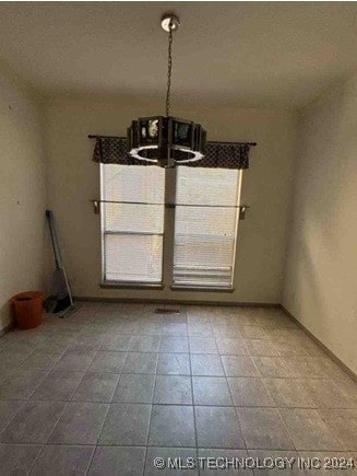 unfurnished dining area featuring tile patterned flooring and a notable chandelier