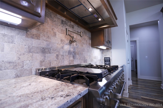 kitchen featuring decorative backsplash, stainless steel range with gas cooktop, dark wood-type flooring, and wall chimney range hood