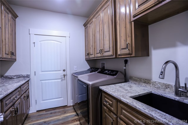 laundry area with washing machine and clothes dryer, sink, cabinets, and dark hardwood / wood-style floors