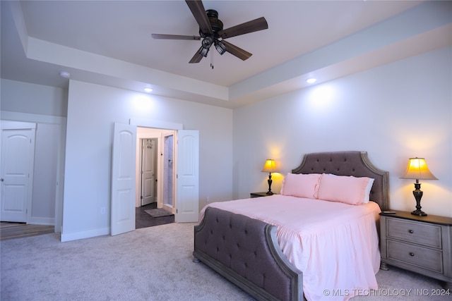 carpeted bedroom featuring ceiling fan and a tray ceiling