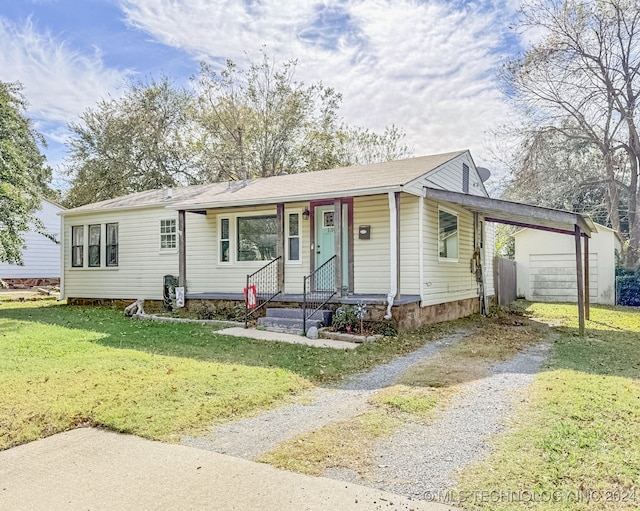 view of front of house with a garage, an outdoor structure, and a front yard