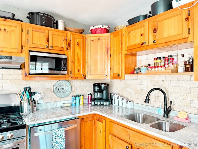 kitchen with sink, light stone countertops, stainless steel appliances, and tasteful backsplash