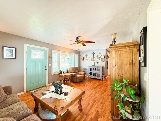 living room with a textured ceiling, light hardwood / wood-style floors, and ceiling fan