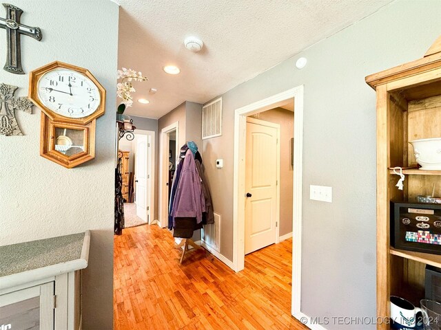 1306 E Comanche Ave, Mcalester, OK 74501 - hall with light wood-type flooring, a textured ceiling, and baseboards