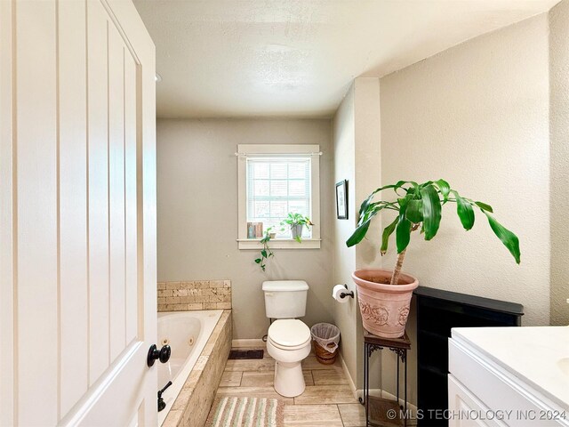 1306 E Comanche Ave, Mcalester, OK 74501 - bathroom featuring a tub with jets, toilet, vanity, and baseboards