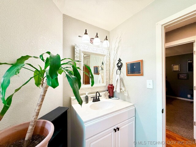 1306 E Comanche Ave, Mcalester, OK 74501 - bathroom featuring vanity, vaulted ceiling, a textured wall, and wood finished floors
