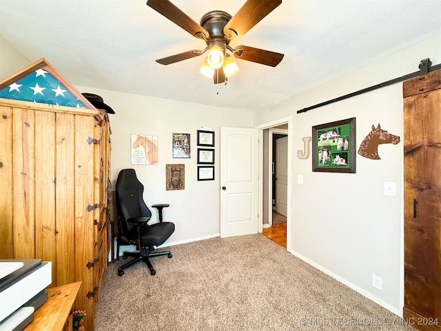 office space featuring carpet floors, ceiling fan, and a barn door