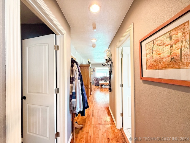 hallway featuring a textured ceiling and light hardwood / wood-style flooring