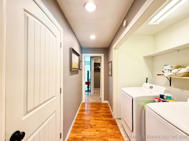 clothes washing area with light hardwood / wood-style flooring and washing machine and clothes dryer