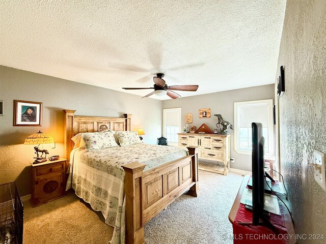 bedroom with a textured ceiling, ceiling fan, and light carpet