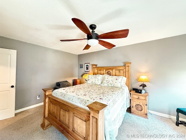 bedroom with a textured ceiling, light colored carpet, and ceiling fan