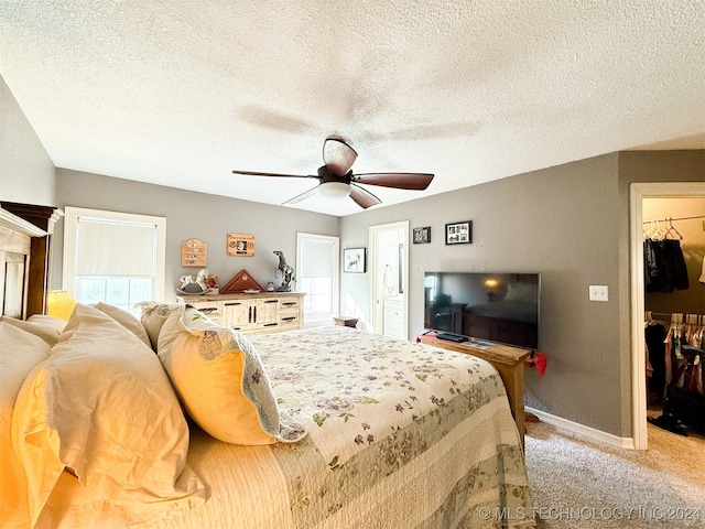 carpeted bedroom with ceiling fan, a walk in closet, a textured ceiling, and a closet