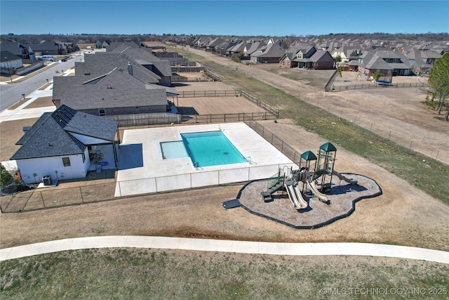 view of swimming pool featuring a residential view, fence, and playground community