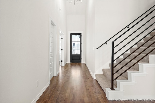 foyer featuring a chandelier, baseboards, dark wood-style floors, and stairs