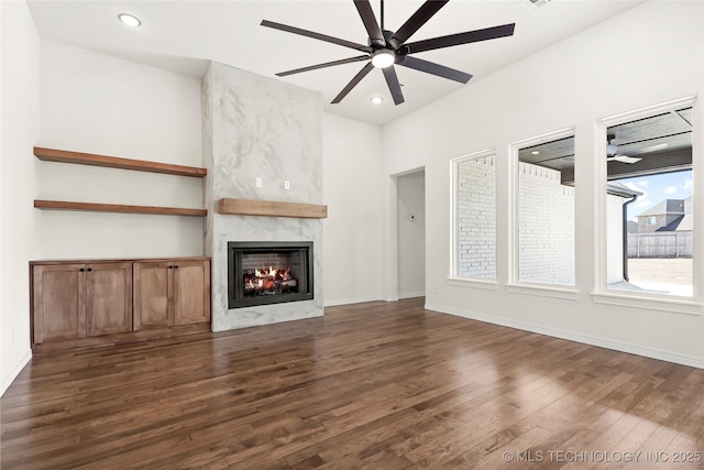 unfurnished living room featuring baseboards, ceiling fan, a fireplace, dark wood finished floors, and recessed lighting