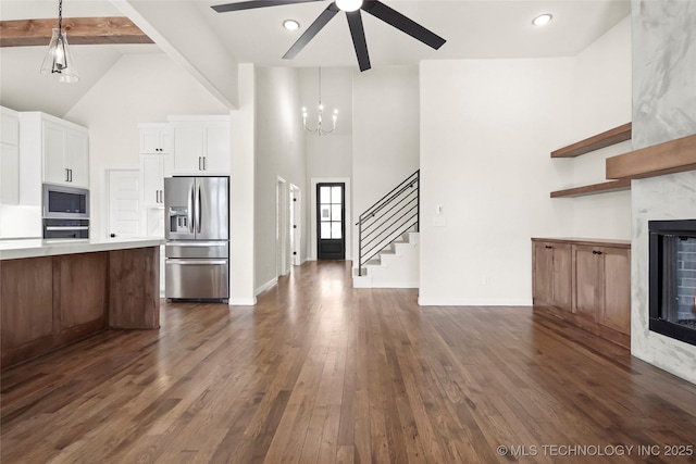 unfurnished living room featuring dark wood-style flooring, baseboards, stairway, ceiling fan, and high vaulted ceiling