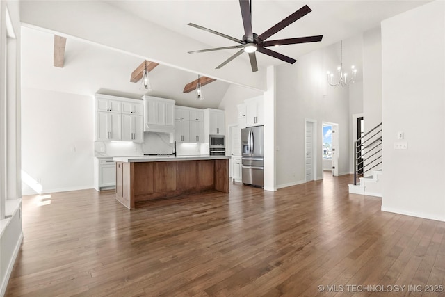 kitchen featuring ceiling fan with notable chandelier, high vaulted ceiling, light countertops, stainless steel appliances, and open floor plan