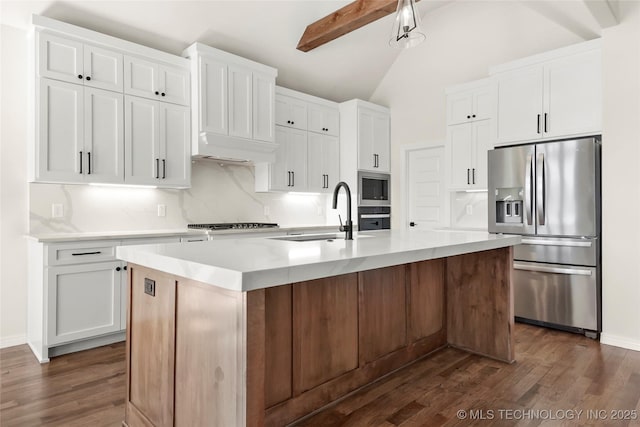 kitchen featuring dark wood-type flooring, lofted ceiling with beams, appliances with stainless steel finishes, and a sink